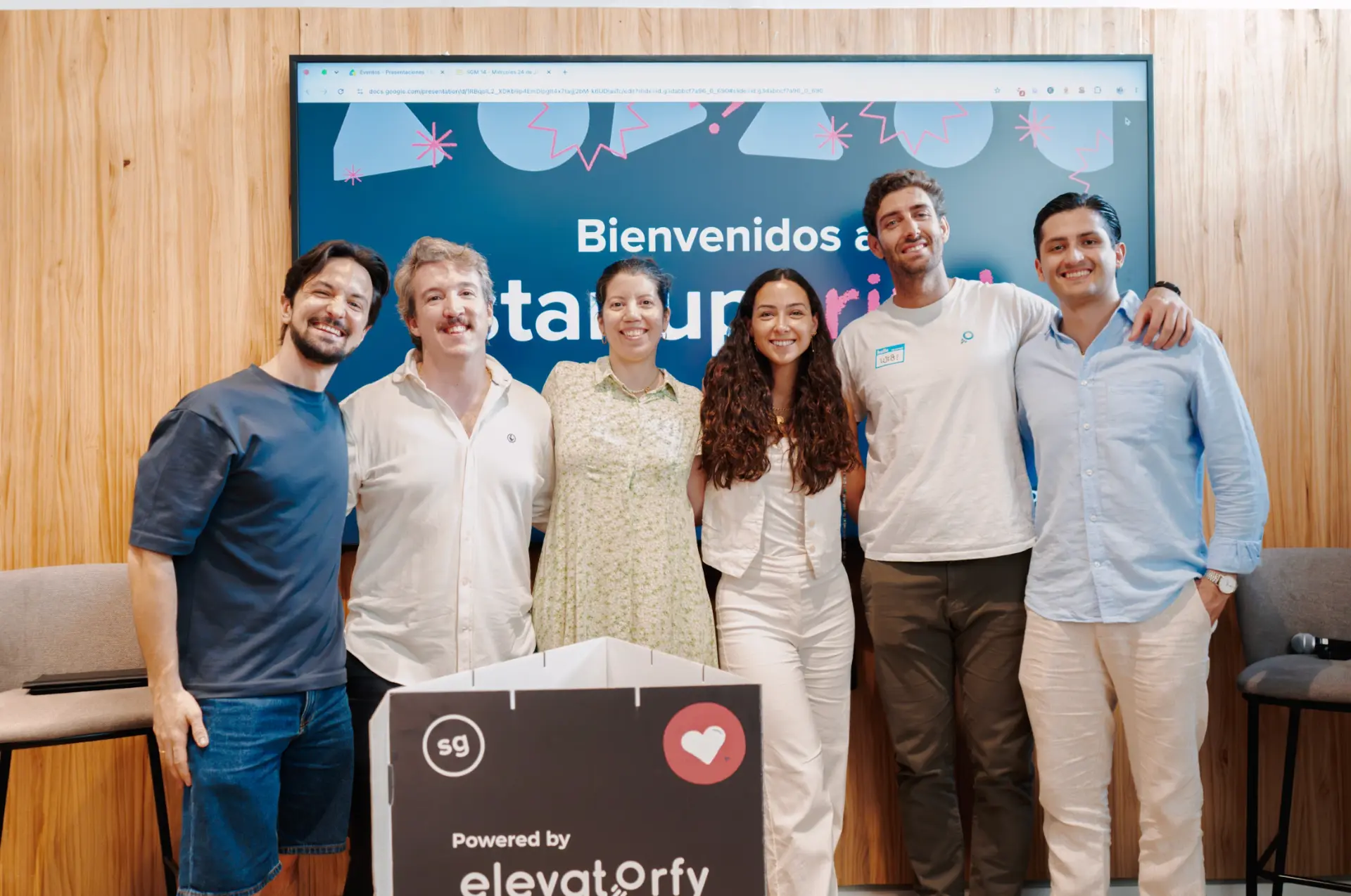 Equipo organizador de Startup Grind Madrid junto al photocall del evento powered by Elevatorfy